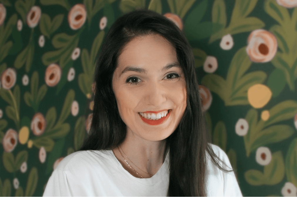 Woman smiling in front of a floral mural