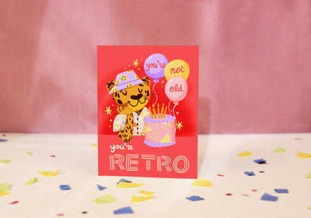 Greeting card with a retro-themed illustration of a leopard and balloons on a red background.