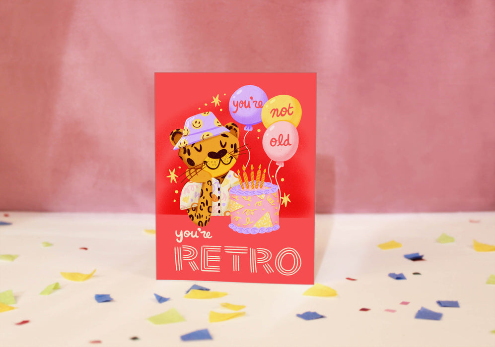 Greeting card with a retro-themed illustration of a leopard and balloons on a red background.