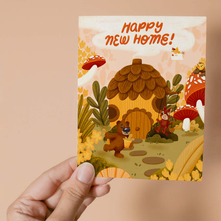 Greeting card with an acorn house, bear, owl, bird, and squirrel in a forest setting with 'Happy New Home!' text.