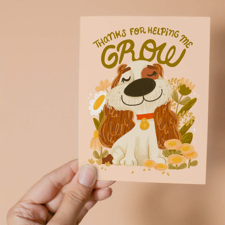 Greeting card with an illustrated dog surrounded by flowers and the letters "Thanks for Helping Me Grow".