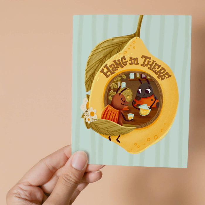 Greeting card with two insects inside a lemon, with text 'Hang in There'.
