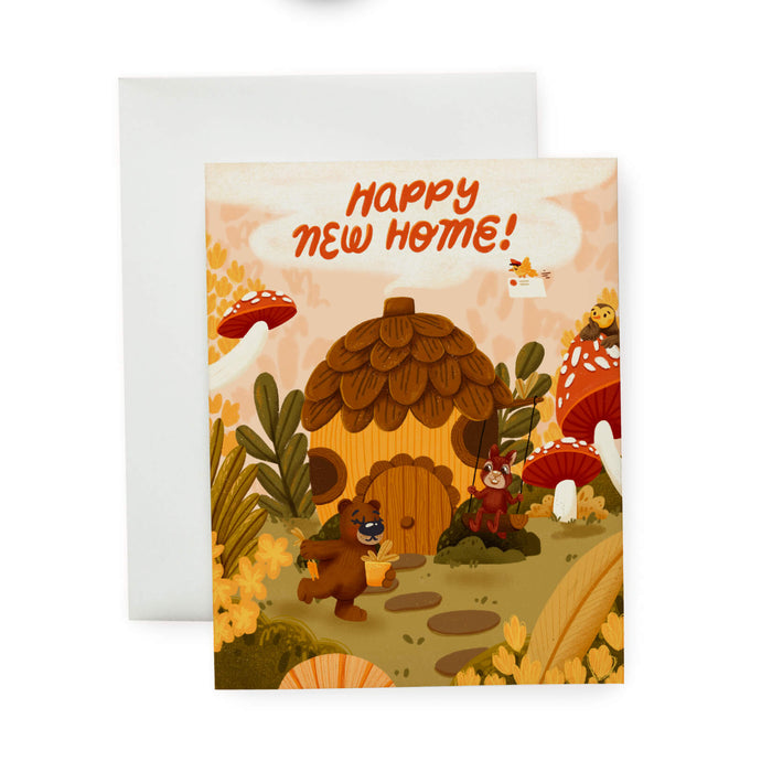 Greeting card with an acorn house, bear, owl, bird, and squirrel in a forest setting with 'Happy New Home!' text.