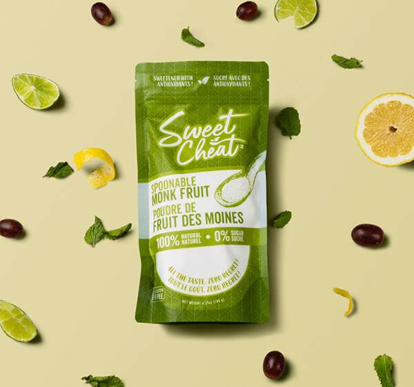 Green package of Sweet Cheat monk fruit on a yellow background with fruits and leaves.