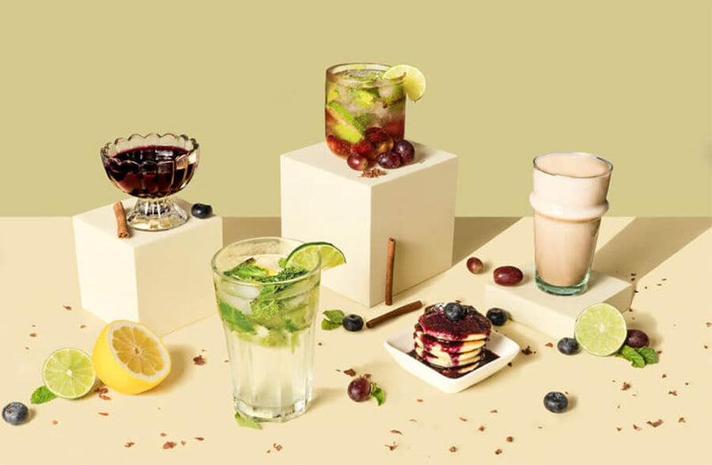 Assorted beverages and desserts on a table with a light green background