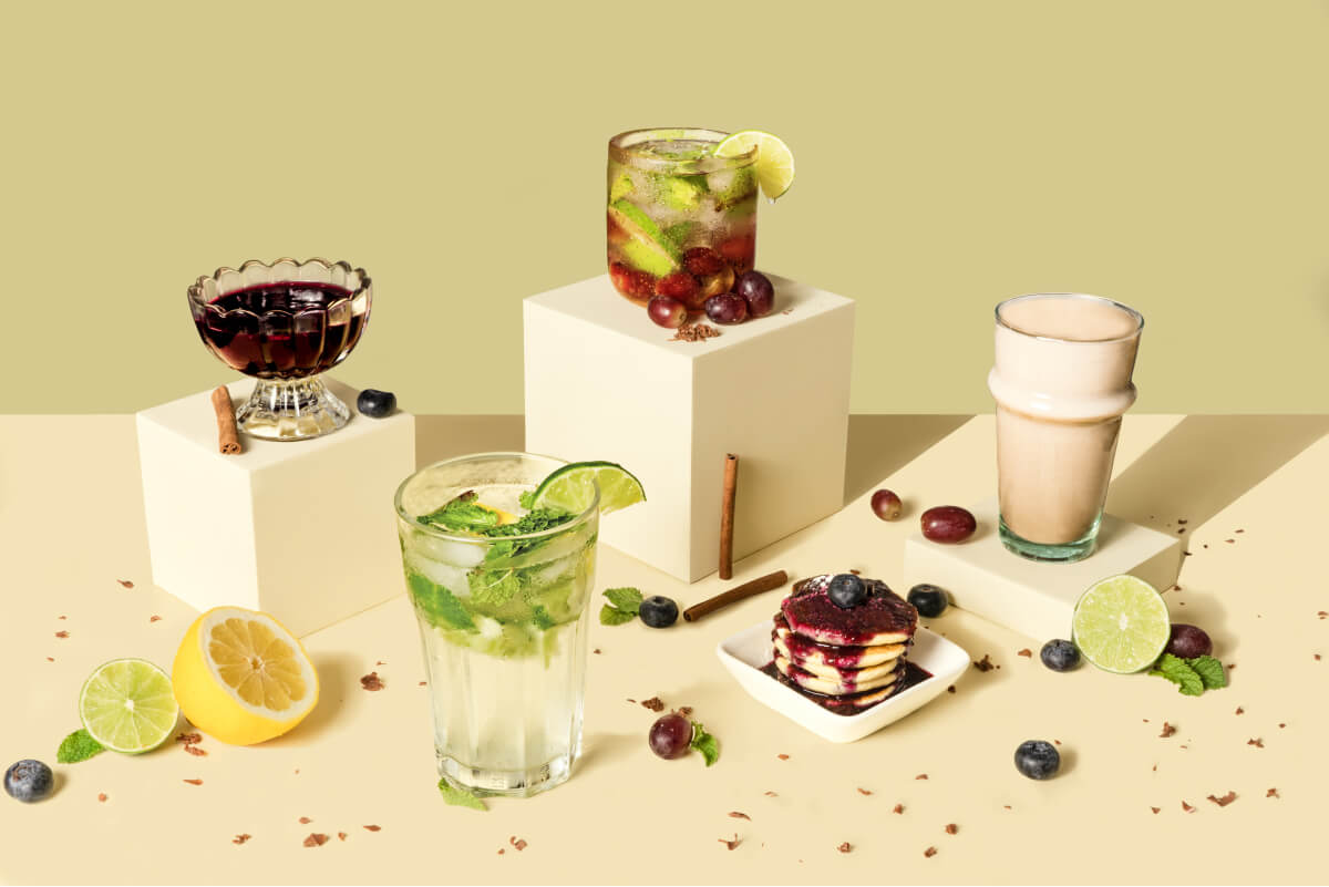 Assorted beverages and desserts on a light surface with a green background